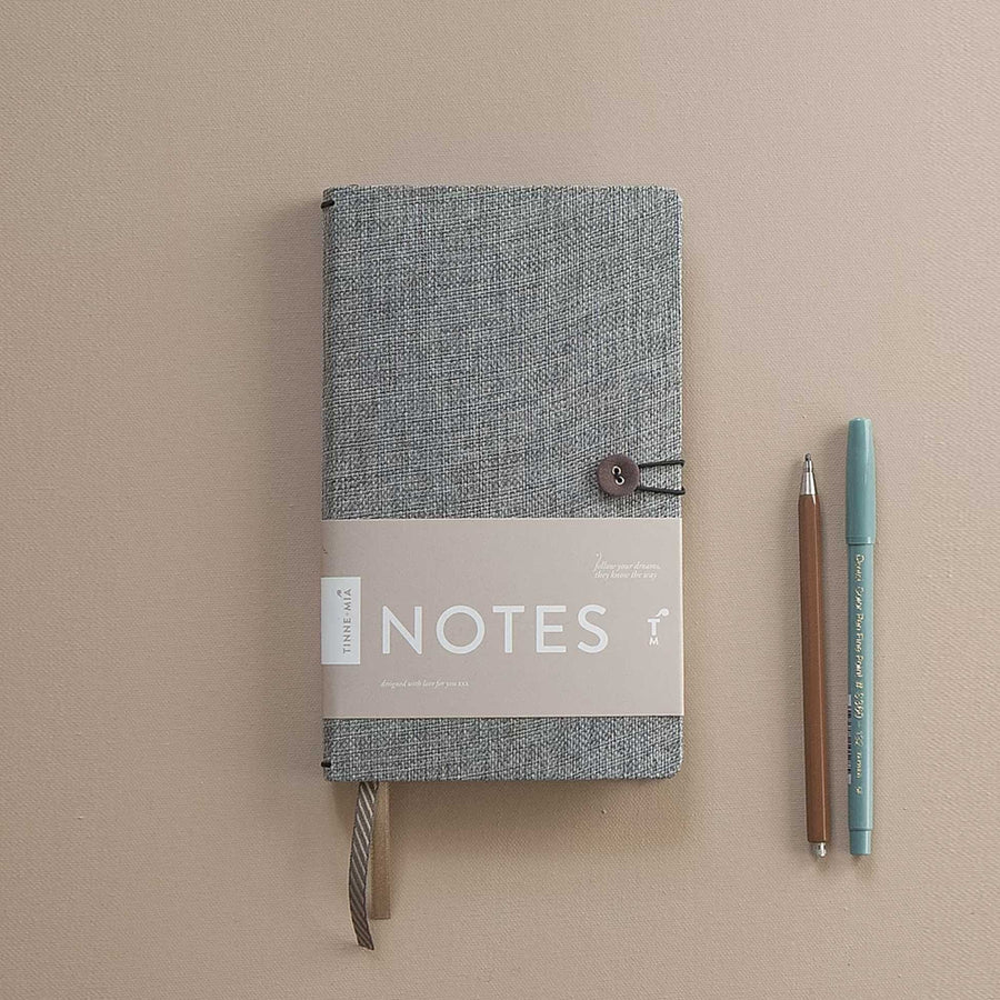 Een fijn notitieboek van Tinne+Mia van groen boeklinnen met goud/koperen details en twee leeslinten.